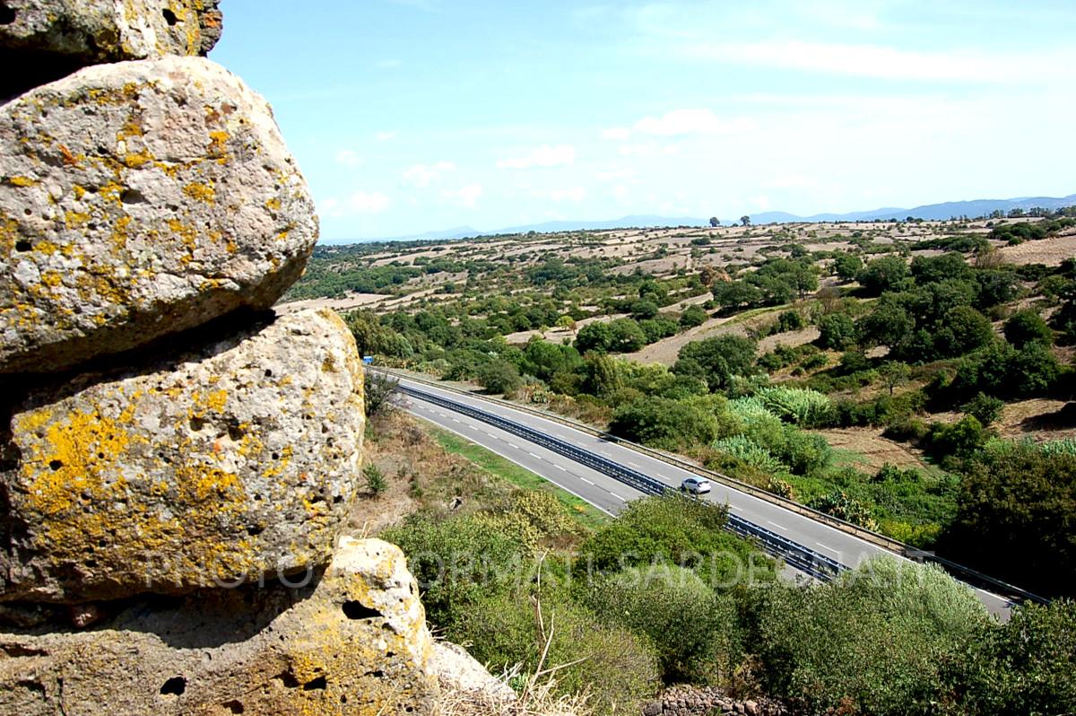 La SS 131 Bis che scorre ai piedi del rilievo su cui si trova il nuraghe