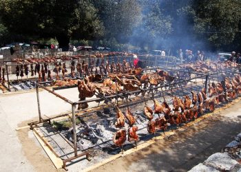 La tipica cottura del porcetto sardo in una festa campestre.
